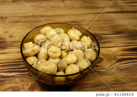 Glass bowl with pickled champignons. Marinated mushrooms on wooden table 81196819