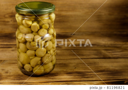 Delicious marinated mushrooms in glass jar on wooden table 81196821