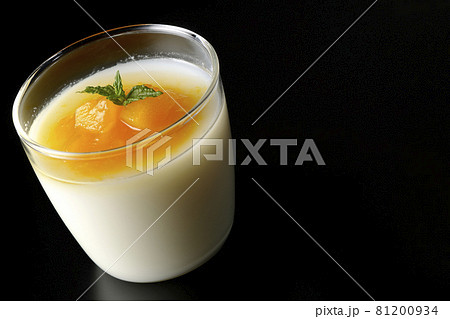 果肉入りのマンゴーソースがかかった杏仁豆腐を黒背景で撮影 81200934