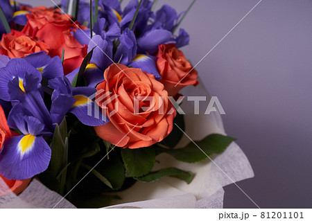 A colorful bouquet of flowers made of orange roses and purple irises. On a light background. A place to copy. The concept of the holiday A colorful bouquet of flowers made of orange roses and purple irises. On a light background. A place to copy. The concept of the holiday 81201101