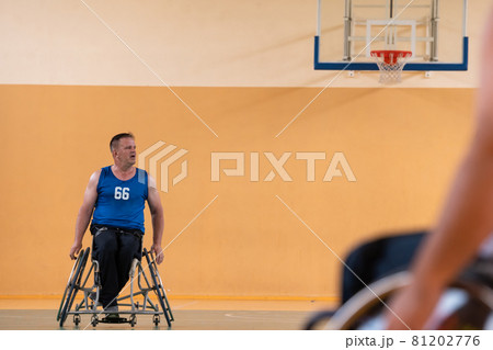 a photo of a war veteran playing basketball with a team in a modern sports arena. The concept of sport for people with disabilities a photo of a war veteran playing basketball with a team in a modern sports arena. The concept of sport for people with disabilities 81202776
