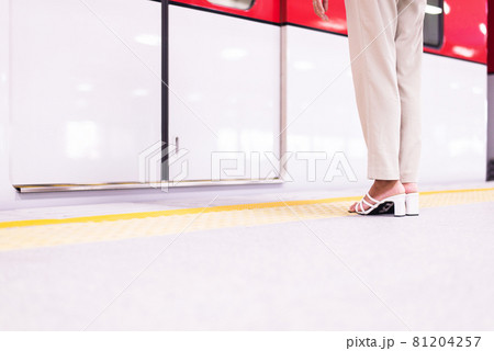 Woman standing behind safety yellow line for waiting for the train Woman standing behind safety yellow line for waiting for the train 81204257