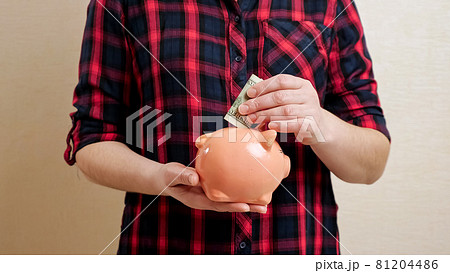 Woman holds piggy bank on palm and throws banknote inside Woman holds piggy bank on palm and throws banknote inside 81204486