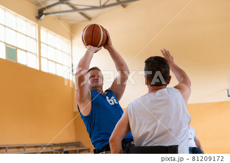Disabled War veterans mixed race opposing basketball teams in wheelchairs photographed in action while playing an important match in a modern hall. Disabled War veterans mixed race opposing basketball teams in wheelchairs photographed in action while playing an important match in a modern hall. 81209172