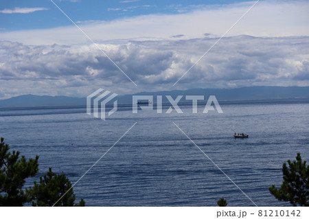 釣り船とタンカーと青い海と対岸の山と雲の多い青空と緑の樹のある風景 81210142