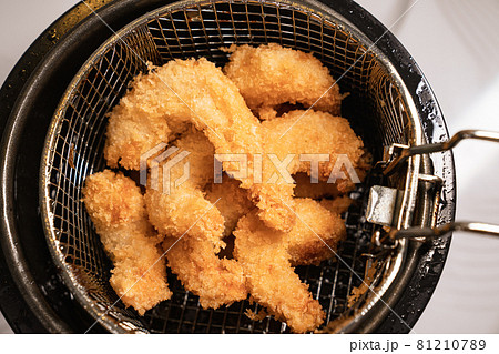 from the fryer pull out a basket with fried shrimp in batter. 81210789