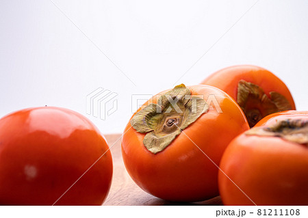 木の皿に柿をのせた白背景写真 81211108