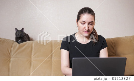 Brunette with ponytail looks into laptop display at home 81212327