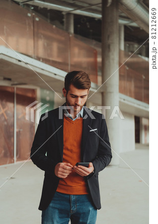 businessman architect using a smartphone while overseeing the construction site 81212669