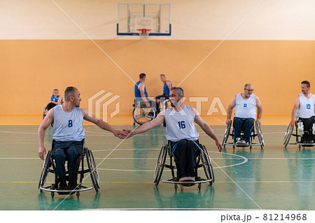 a team of war veterans in wheelchairs playing basketball, celebrating points won in a game. High five concept 81214968