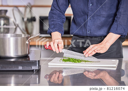 パセリを切るエプロン姿の若い男性の手 料理男子イメージの写真素材