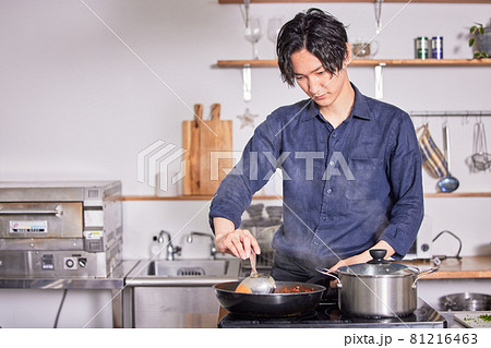 キッチンで料理するエプロン姿の若い男性 料理男子イメージ キッチンで料理するエプロン姿の若い男性 料理男子イメージ 81216463