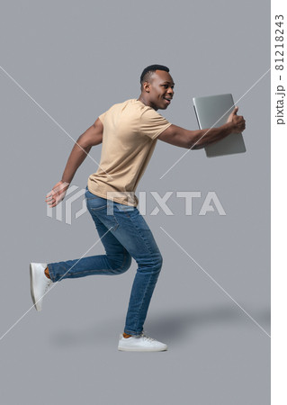 Dark-skinned young man with a laptop in hands 81218243
