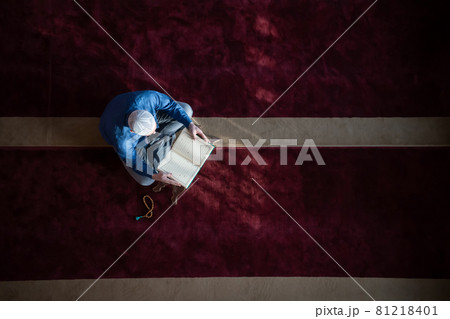 muslim man praying Allah alone inside the mosque and reading islamic holly book 81218401