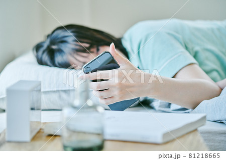 朝起きてスマホを確認する女性 81218665