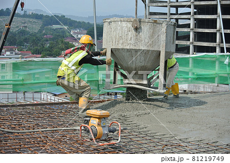 SELANGOR, MALAYSIA -AUGUST 01, 2016: Group of construction workers pouring wet concrete using concrete bucket into the timber form work at the construction site.   81219749