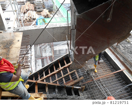SELANGOR, MALAYSIA -AUGUST 01, 2016: Group of construction workers pouring wet concrete using concrete bucket into the timber form work at the construction site.   81219751
