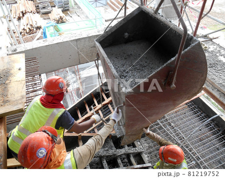 SELANGOR, MALAYSIA -AUGUST 01, 2016: Group of construction workers pouring wet concrete using concrete bucket into the timber form work at the construction site.   81219752