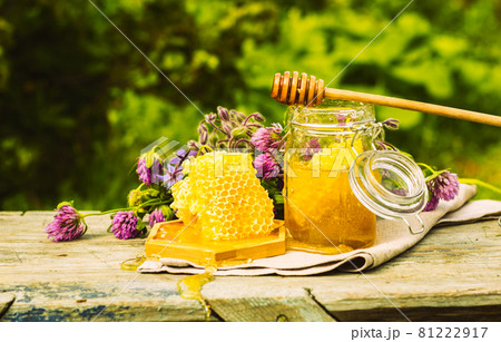 Fresh honey in a glass jar on a summer rural background. Floral fragrant sweet honey dessert, front view Fresh honey in a glass jar on a summer rural background. Floral fragrant sweet honey dessert, front view 81222917