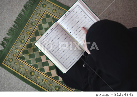 Middle eastern woman praying and reading the holy Quran 81224345