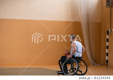 a photo of a war veteran playing basketball with a team in a modern sports arena. The concept of sport for people with disabilities 81224349