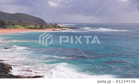 People swim in the turquoise waters of the Tropical Beach. Sandy Beach. Blue Waves of the Pacific Ocean Beats Oahu Island Volcanic Cliffs. Ke One Kula Lookout. Clear sunny day. DCI 4k People swim in the turquoise waters of the Tropical Beach. Sandy Beach. Blue Waves of the Pacific Ocean Beats Oahu Island Volcanic Cliffs. Ke One Kula Lookout. Clear sunny day. DCI 4k 81224516