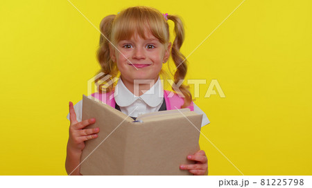 Lovely teenage girl kid in school uniform wears pink backpack peeping while hiding behind a book 81225798