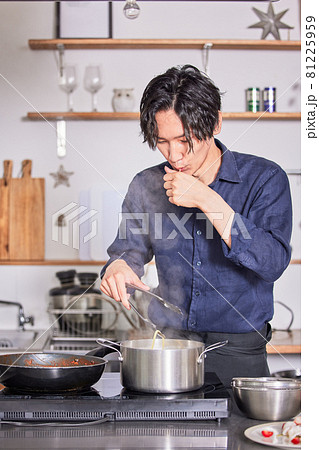 パスタの固さを確認するエプロン姿の若い男性　料理男子イメージ 81225959