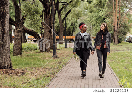 Affectionate lesbian couple in casualwear taking walk in public park Affectionate lesbian couple in casualwear taking walk in public park 81226133