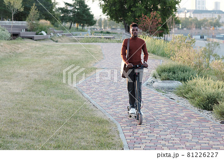 Young African businessman in smart casualwear moving on scooter 81226227