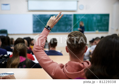 The student raises his hands asking a question in class in college The student raises his hands asking a question in class in college 81229338