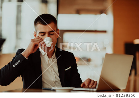 Happy business man sitting at cafeteria with laptop and smartphone 81229350