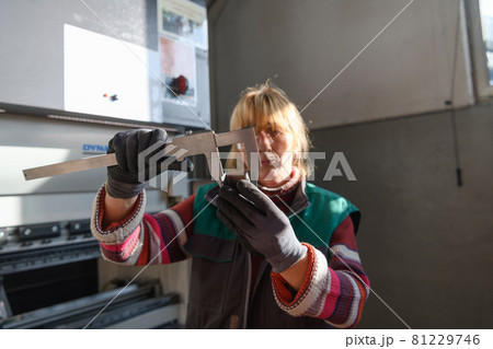 a woman working in a modern factory for the production and processing of metals, preparing and measures materials that go to the processing of CNC machines 81229746