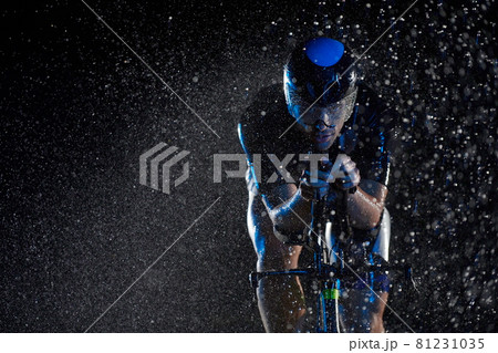 triathlon athlete riding bike fast on rainy night triathlon athlete riding bike fast on rainy night 81231035
