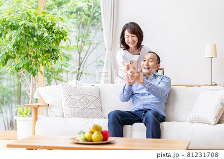 リビングでスマホを見るシニア夫婦 81231708