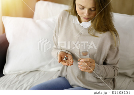 Close-up woman holding pills time to take medications, cure for headache. Medicine concept during self isolation and Coronavirus pandemic Close-up woman holding pills time to take medications, cure for headache. Medicine concept during self isolation and Coronavirus pandemic 81238155