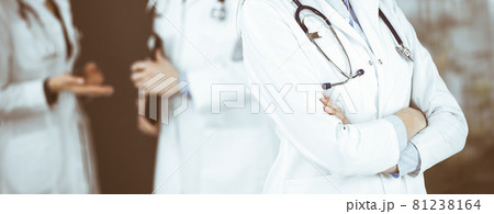 Unknown young woman doctor is standing with arms crossed in clinic. Medicine concept during Coronavirus pandemic Unknown young woman doctor is standing with arms crossed in clinic. Medicine concept during Coronavirus pandemic 81238164
