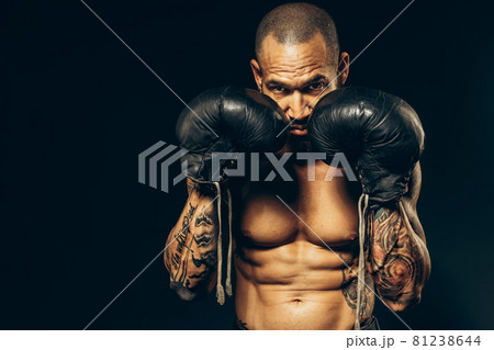Studio portrait of a muscular boxer with a naked torso on a dark background. The Latin American 81238644