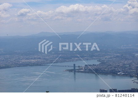 比叡山山頂から見た近江大橋のある青い琵琶湖と街と霞んで見える連なる山々ともくもくした雲の多い青空 81240114