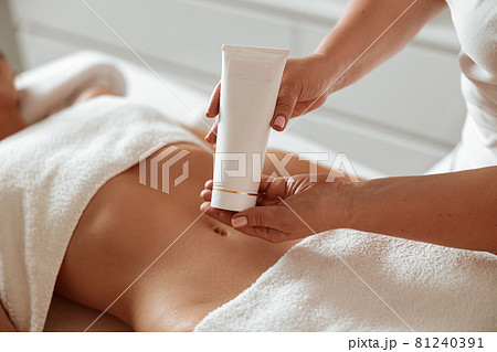 Beautician standing by client and holding cosmetic cream Beautician standing by client and holding cosmetic cream 81240391