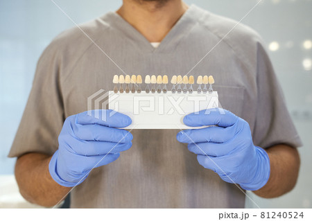 Dental specialist posing with set of color samples of teeth Dental specialist posing with set of color samples of teeth 81240524