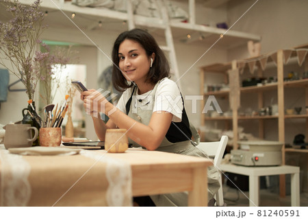 Female potter with smartphone looking at camera 81240591
