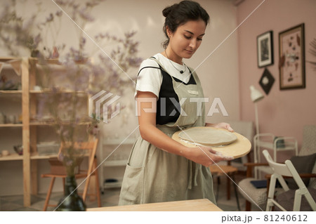 Woman making handmade clay plate in studio 81240612