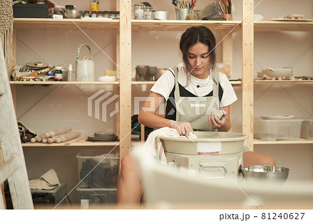 Young woman with clay working in pottery studio 81240627