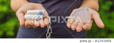 Young woman hands holding different types of feminine hygiene products - menstrual cup and tampons BANNER, LONG FORMAT 81241669