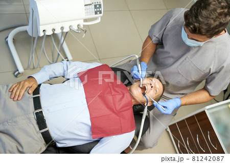 Young dentist doing regular medical check-up of patient teeth Young dentist doing regular medical check-up of patient teeth 81242087