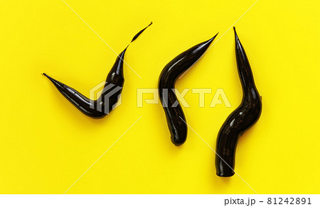 Three thick black cream smears charcoal toothpaste on yellow background, view from above 81242891