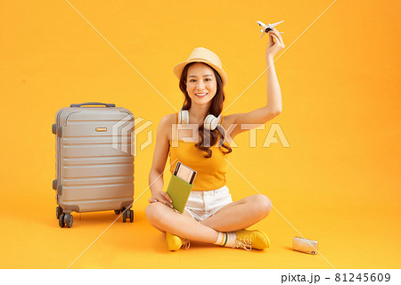Cute and cheerful woman with a passport in the hands of plane tickets near the gray suitcase Cute and cheerful woman with a passport in the hands of plane tickets near the gray suitcase 81245609
