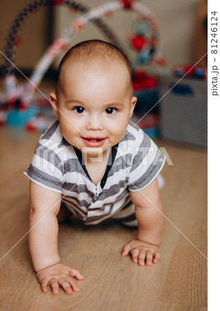 Sweet little baby learning to crawl at home. Smiling infant with chubby cheeks 81246124
