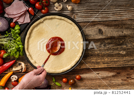 Raw delicious pizza dough with red souce on the wooden table Raw delicious pizza dough with red souce on the wooden table 81252441